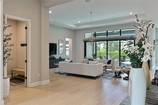 living room with a tray ceiling, a wealth of natural light, and light wood-type flooring