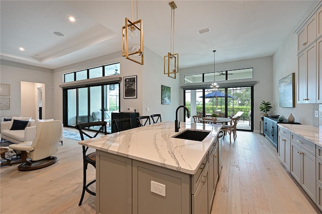 kitchen with gray cabinetry, a center island with sink, decorative light fixtures, and sink