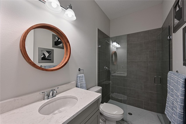 bathroom featuring vanity, a shower with shower door, and toilet