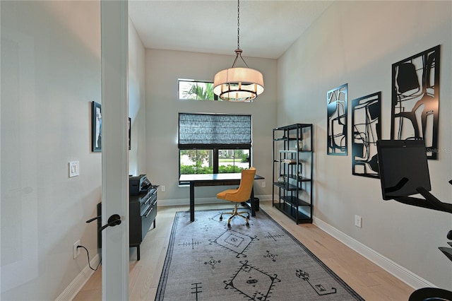 office space with a towering ceiling, a healthy amount of sunlight, and light hardwood / wood-style floors