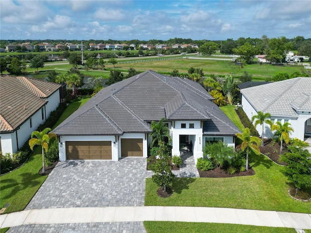 view of front of home with a garage, decorative driveway, a front yard, and stucco siding