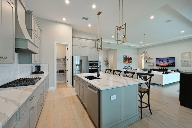 kitchen featuring a breakfast bar area, appliances with stainless steel finishes, custom exhaust hood, gray cabinets, and a sink