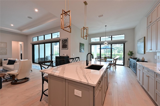 kitchen featuring a breakfast bar, light wood finished floors, gray cabinets, open floor plan, and a sink