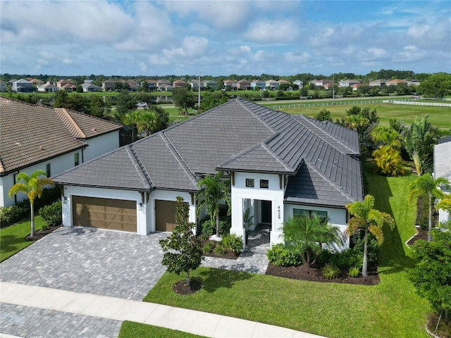 view of front of home with a garage, a residential view, decorative driveway, a front lawn, and stucco siding