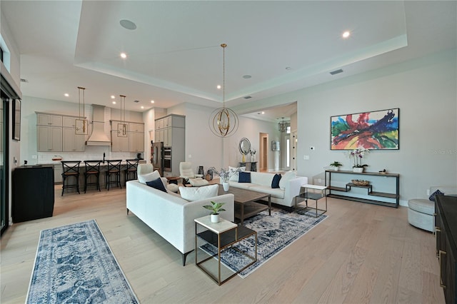 living room with a tray ceiling and light wood-style flooring