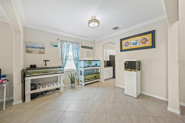 interior space with crown molding, stainless steel refrigerator, light tile patterned floors, and white cabinets