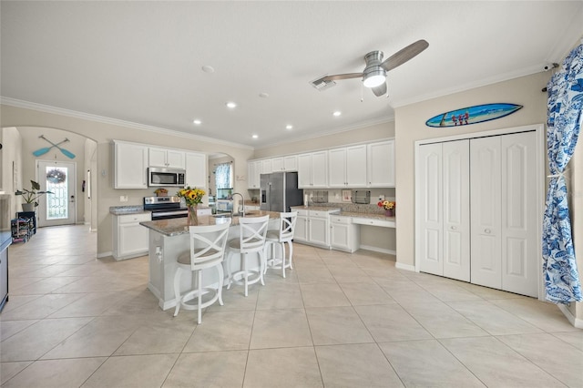 kitchen featuring ceiling fan, a center island with sink, white cabinetry, stainless steel appliances, and crown molding