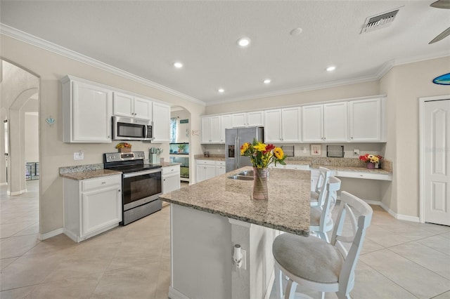 kitchen featuring a center island with sink, white cabinetry, and stainless steel appliances