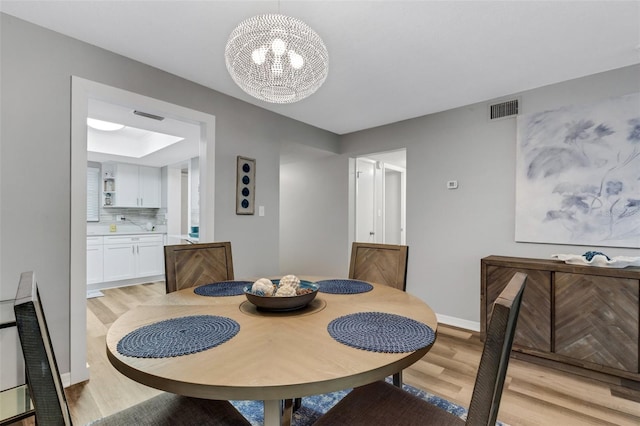 dining room featuring light wood-type flooring and a notable chandelier