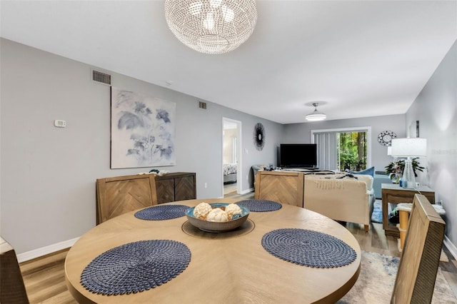 dining room with light hardwood / wood-style floors and a notable chandelier