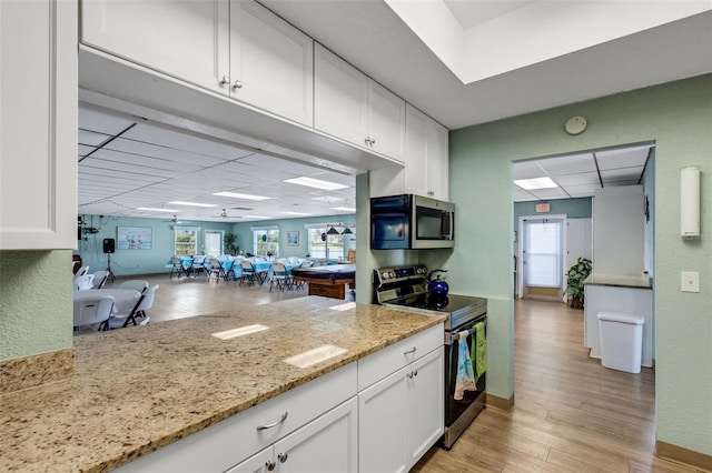 kitchen with light wood-type flooring, stainless steel appliances, and white cabinets