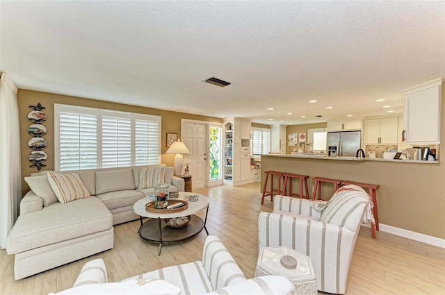 136 Crescent Dr, Anna Maria, FL 34216 - living room with visible vents, recessed lighting, light wood-style flooring, and a textured ceiling