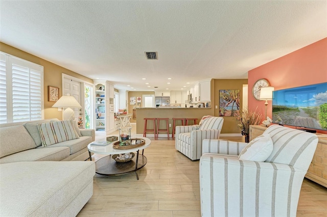 136 Crescent Dr, Anna Maria, FL 34216 - living area with visible vents, a textured ceiling, light wood-style floors, and recessed lighting