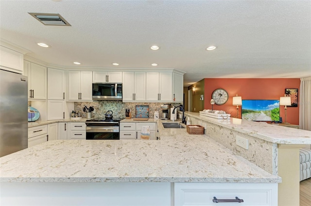 136 Crescent Dr, Anna Maria, FL 34216 - kitchen with a sink, appliances with stainless steel finishes, white cabinets, and a peninsula