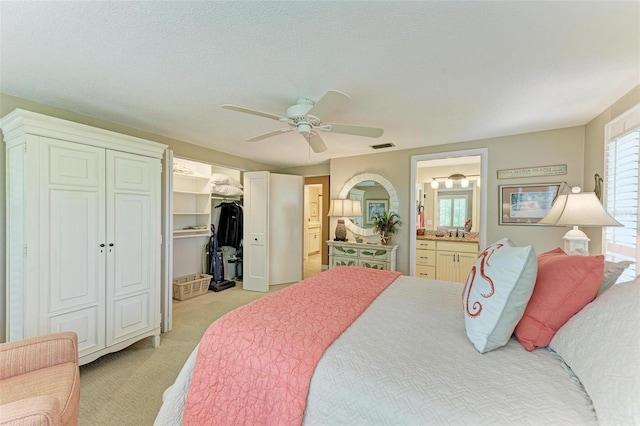 136 Crescent Dr, Anna Maria, FL 34216 - bedroom with a walk in closet, light carpet, a ceiling fan, and connected bathroom