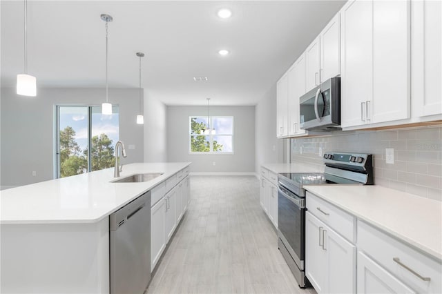 kitchen featuring white cabinets, stainless steel appliances, a kitchen island with sink, and sink