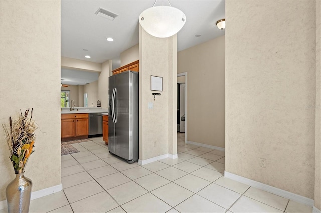 kitchen featuring sink, decorative light fixtures, black dishwasher, light tile patterned floors, and stainless steel fridge