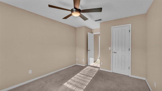 unfurnished bedroom with a textured ceiling, light colored carpet, and ceiling fan