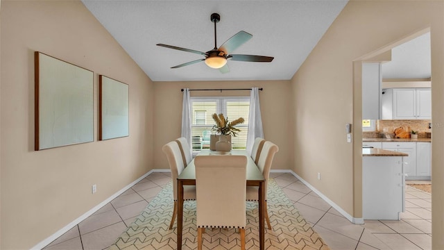 tiled dining space with ceiling fan and vaulted ceiling