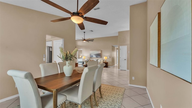 tiled dining space featuring ceiling fan and a high ceiling