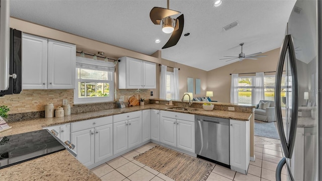 kitchen featuring vaulted ceiling, white cabinets, kitchen peninsula, sink, and appliances with stainless steel finishes