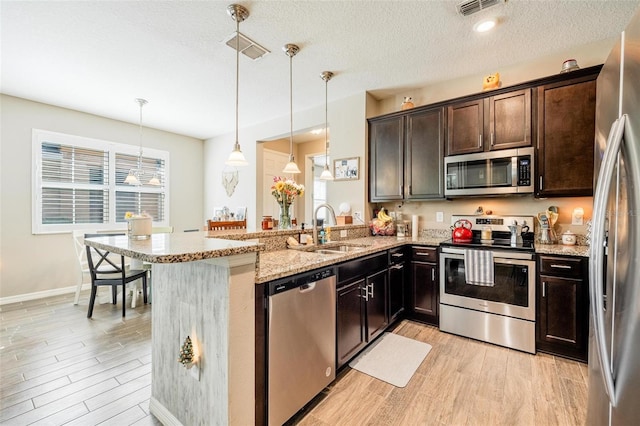 kitchen with pendant lighting, kitchen peninsula, stainless steel appliances, and sink