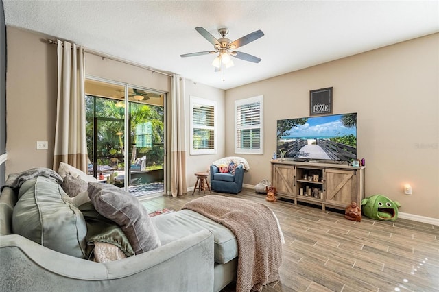 living room with ceiling fan, wood-type flooring, and a textured ceiling