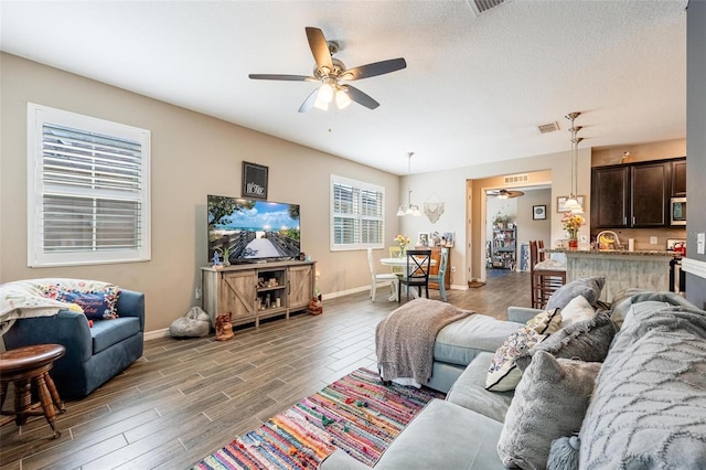 living room featuring a textured ceiling, dark wood-type flooring, ceiling fan, and sink