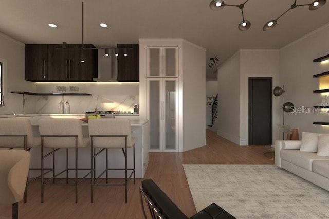 kitchen featuring crown molding, a breakfast bar, dark brown cabinets, and light hardwood / wood-style flooring