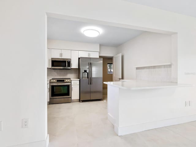 kitchen featuring appliances with stainless steel finishes, tasteful backsplash, kitchen peninsula, and white cabinets