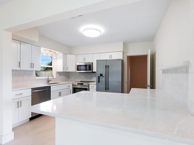 kitchen with appliances with stainless steel finishes, kitchen peninsula, sink, and white cabinets