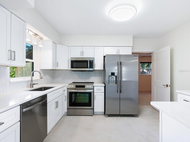 kitchen with a wealth of natural light, appliances with stainless steel finishes, and white cabinets