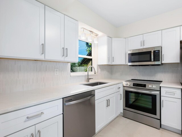 kitchen featuring stainless steel appliances, sink, backsplash, and white cabinetry