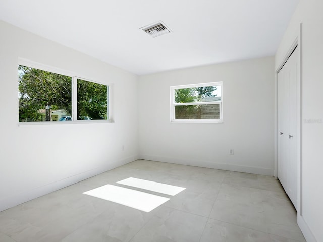 unfurnished bedroom with multiple windows and a closet