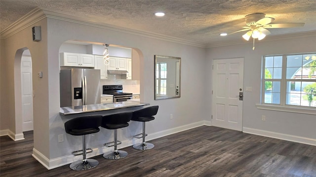 kitchen featuring white cabinets, stainless steel appliances, dark wood-type flooring, a kitchen breakfast bar, and a textured ceiling