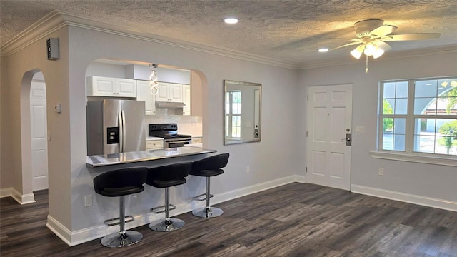kitchen with arched walkways, dark wood-style flooring, appliances with stainless steel finishes, a kitchen breakfast bar, and under cabinet range hood