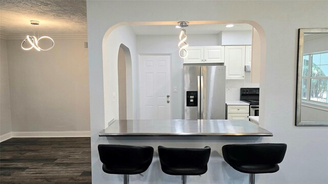 kitchen with a textured ceiling, dark hardwood / wood-style floors, stainless steel fridge, pendant lighting, and white cabinetry