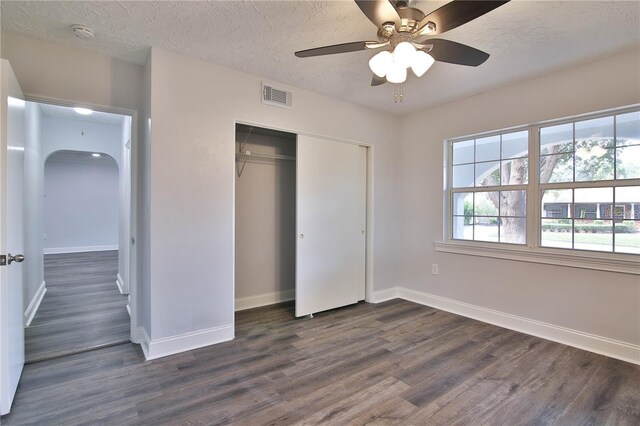 unfurnished bedroom featuring a closet, a textured ceiling, ceiling fan, and dark hardwood / wood-style floors