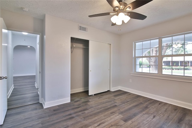 2912 Pinecrest Way, Sarasota, FL 34239 - unfurnished bedroom featuring arched walkways, dark wood finished floors, a closet, a textured ceiling, and a ceiling fan