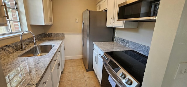 kitchen with white cabinets, light stone counters, appliances with stainless steel finishes, and sink