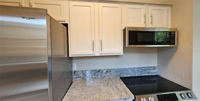 kitchen featuring white cabinetry, stainless steel appliances, and light stone counters