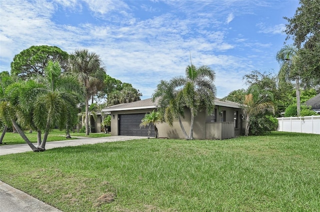 view of property exterior featuring an attached garage, fence, stucco siding, a yard, and driveway