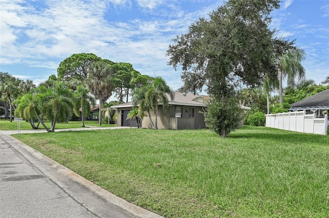 view of yard featuring driveway, a garage, and fence