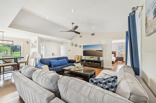 living room with ceiling fan, light hardwood / wood-style floors, and vaulted ceiling