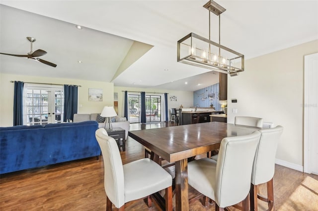 dining room featuring vaulted ceiling, french doors, hardwood / wood-style floors, ceiling fan with notable chandelier, and sink