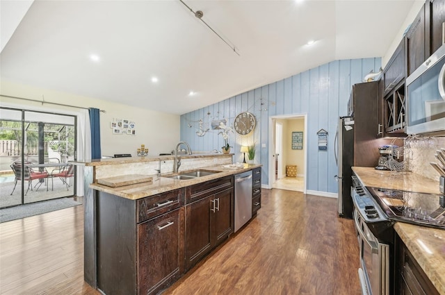 kitchen with wooden walls, stainless steel appliances, sink, dark hardwood / wood-style floors, and lofted ceiling