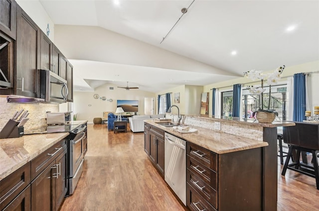 kitchen with stainless steel appliances, a kitchen breakfast bar, sink, lofted ceiling, and light hardwood / wood-style floors