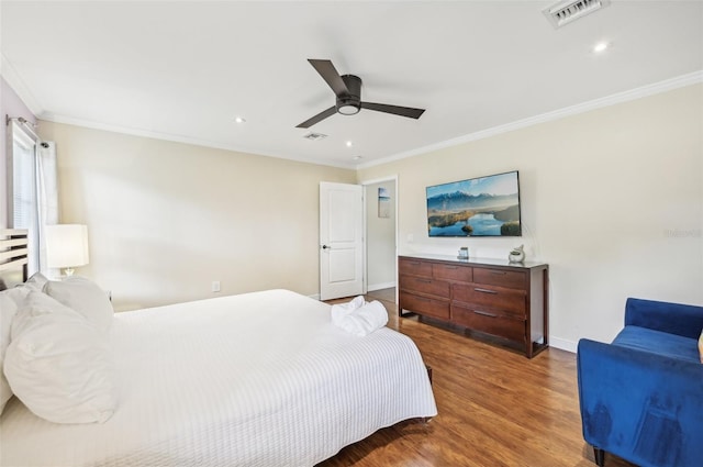 bedroom with visible vents, baseboards, wood finished floors, and ornamental molding