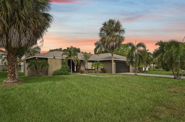 view of front of home with stucco siding, an attached garage, a lawn, and driveway