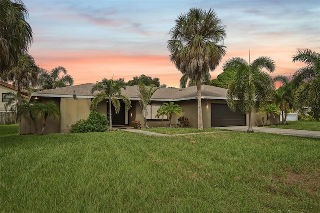 view of front of home with a garage, concrete driveway, a front yard, and stucco siding